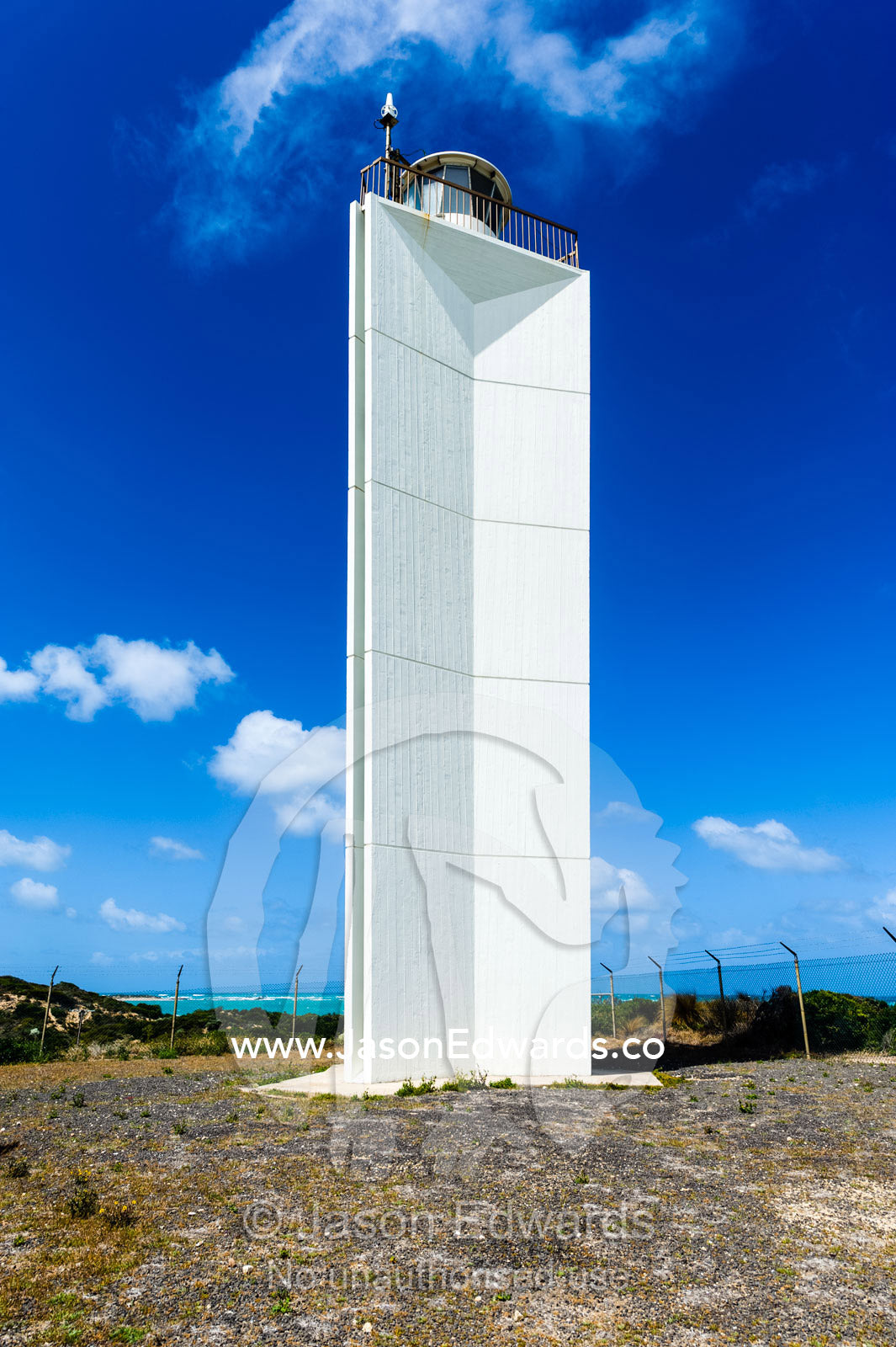 A stark white lighthouse on a rugged limestone coastline. Robe, Limestone Coast, South Australia, Australia.