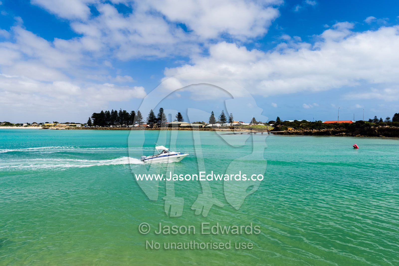 A speed boat crosses the turquoise waters of a safe harbour on a sunny day. Robe, Limestone Coast, South Australia, Australia.