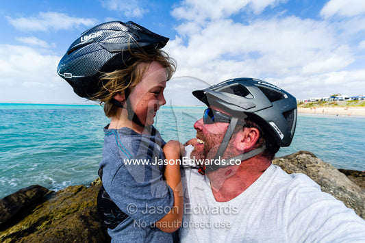 A father and son hugging each other on a bike ride. Robe, Limestone Coast, South Australia, Australia.
