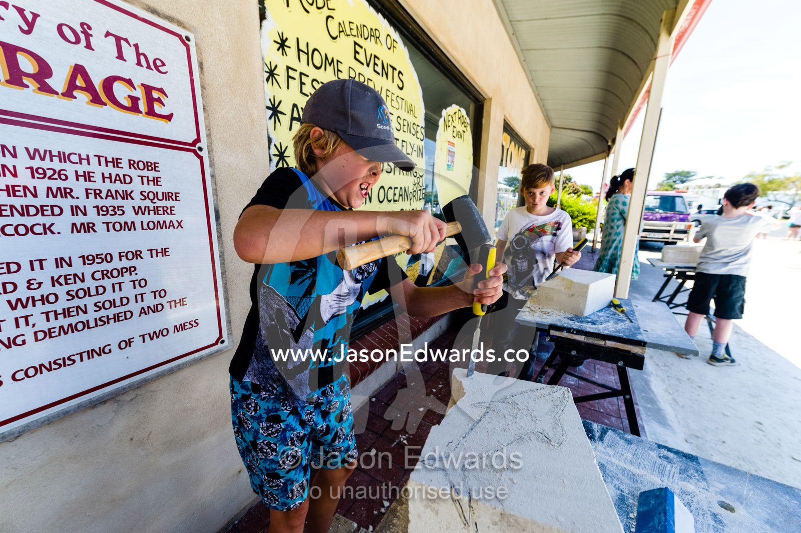 A boy carves a shark into a block of sandstone during a school holiday program activity. Robe, Limestone Coast, South Australia, Australia.