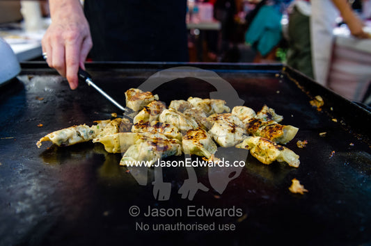 Beef dumplings cooking on a barbecue hotplate at an elementary school fete. Carlton North, Melbourne, Victoria, Australia.