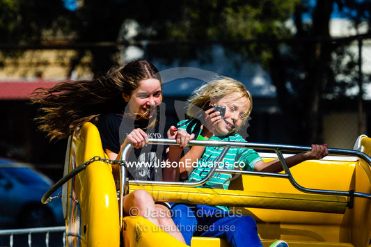 Friends whirling around on a theme park ride at an elementary school fete. Carlton North, Melbourne, Victoria, Australia.