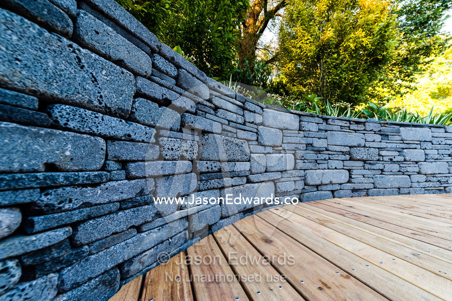A bluestone wall and timber decking on an outdoor patio at a garden show. Melbourne International Flower and Garden Show, Carlton Gardens, Carlton, Melbourne, Victoria, Australia.
