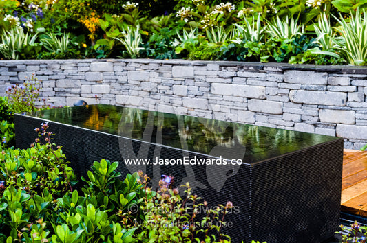 An architecturally designed outdoor patio and garden setting with a blue stone pond at a garden show. Melbourne International Flower and Garden Show, Carlton Gardens, Carlton, Melbourne, Victoria, Australia.