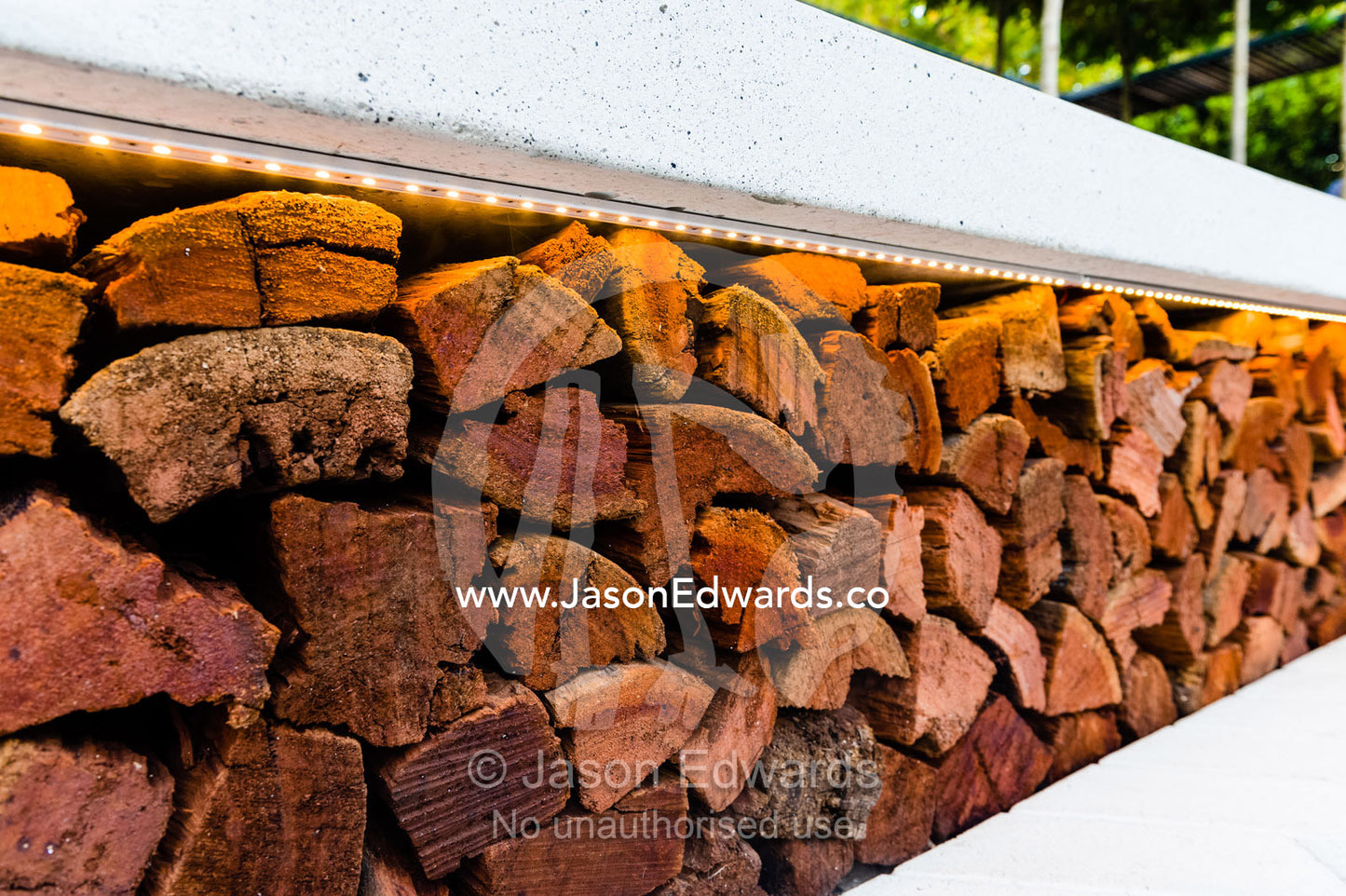LED strip lighting illuminates a pile of fire logs in an outdoor garden patio at a garden show. Melbourne International Flower and Garden Show, Carlton Gardens, Carlton, Melbourne, Victoria, Australia.