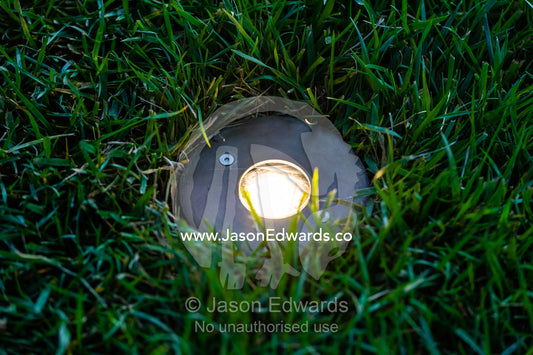 A spotlight embedded in a grass lawn in a garden. Melbourne International Flower and Garden Show, Carlton Gardens, Carlton, Melbourne, Victoria, Australia.
