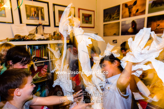 A group of friends play tissue paper games and fights at a birthday party. Carlton North, Melbourne, Victoria, Australia.