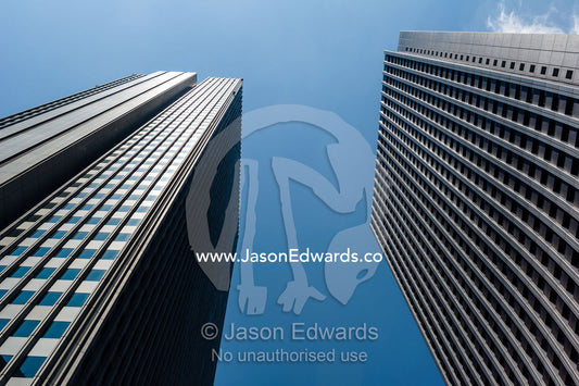 Twin towers of steel and glass offices rise into a blue sky in the central business district. Shinjuku, Tokyo, Japan.