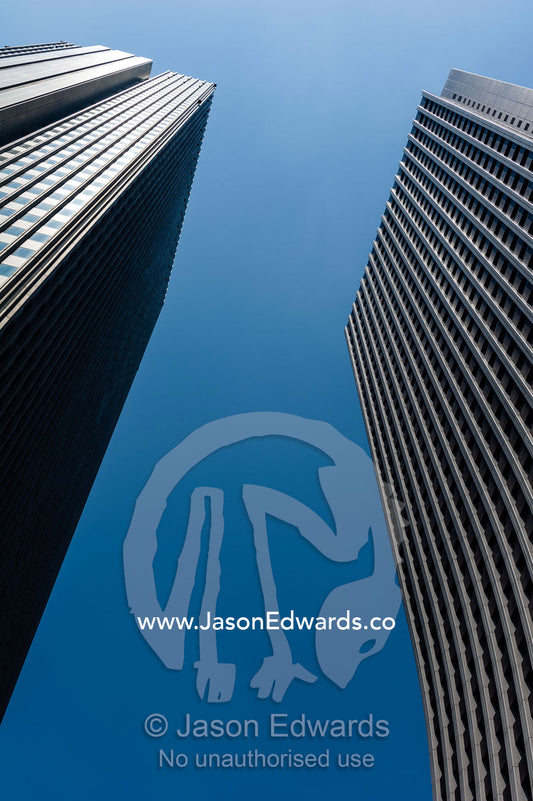 Twin towers of steel and glass offices rise into a blue sky in the central business district. Shinjuku, Tokyo, Japan.