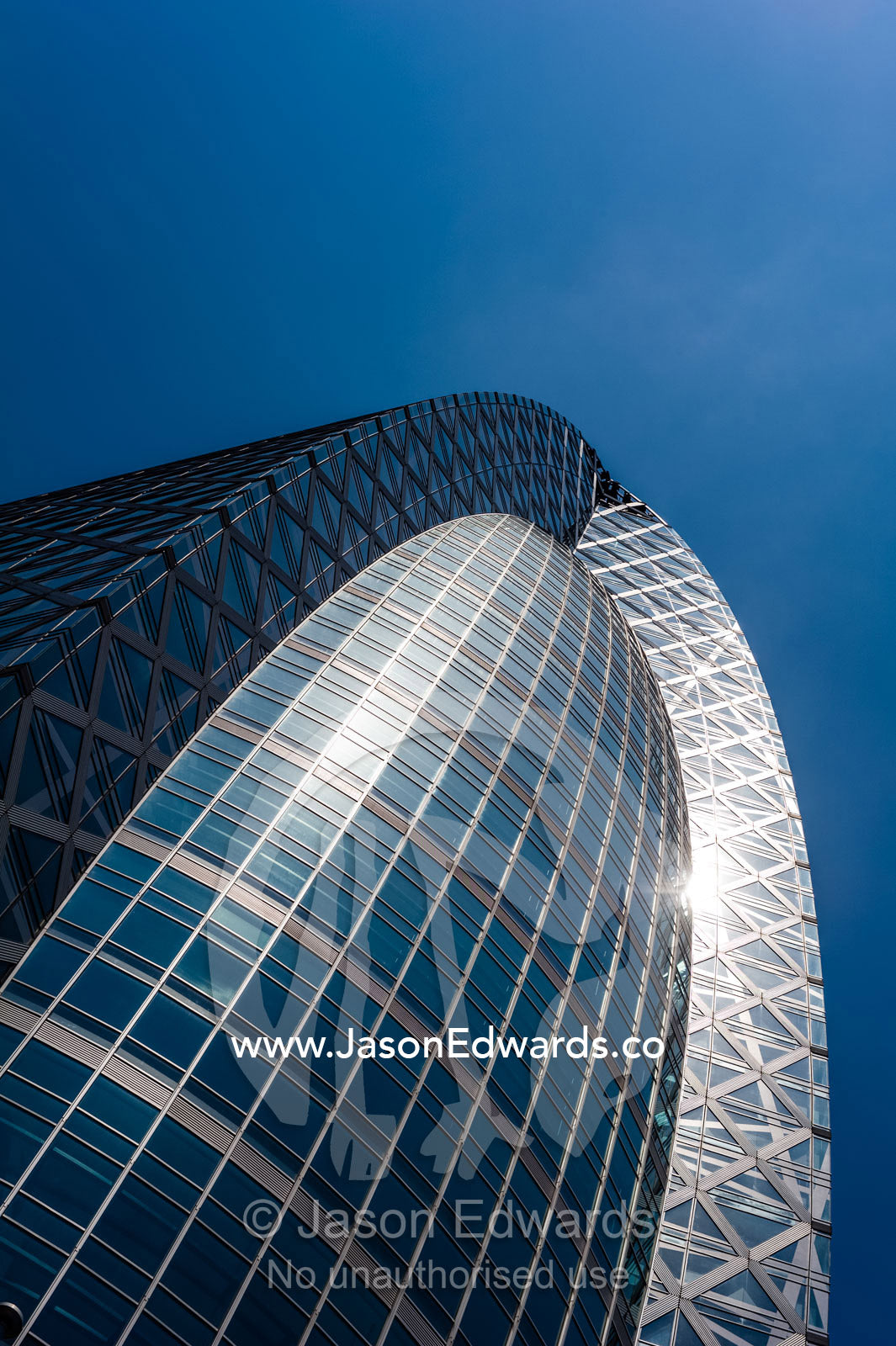The sun reflected in the wedge-shaped dome glass facade of a building in Tokyo. Shinjuku, Tokyo, Japan.