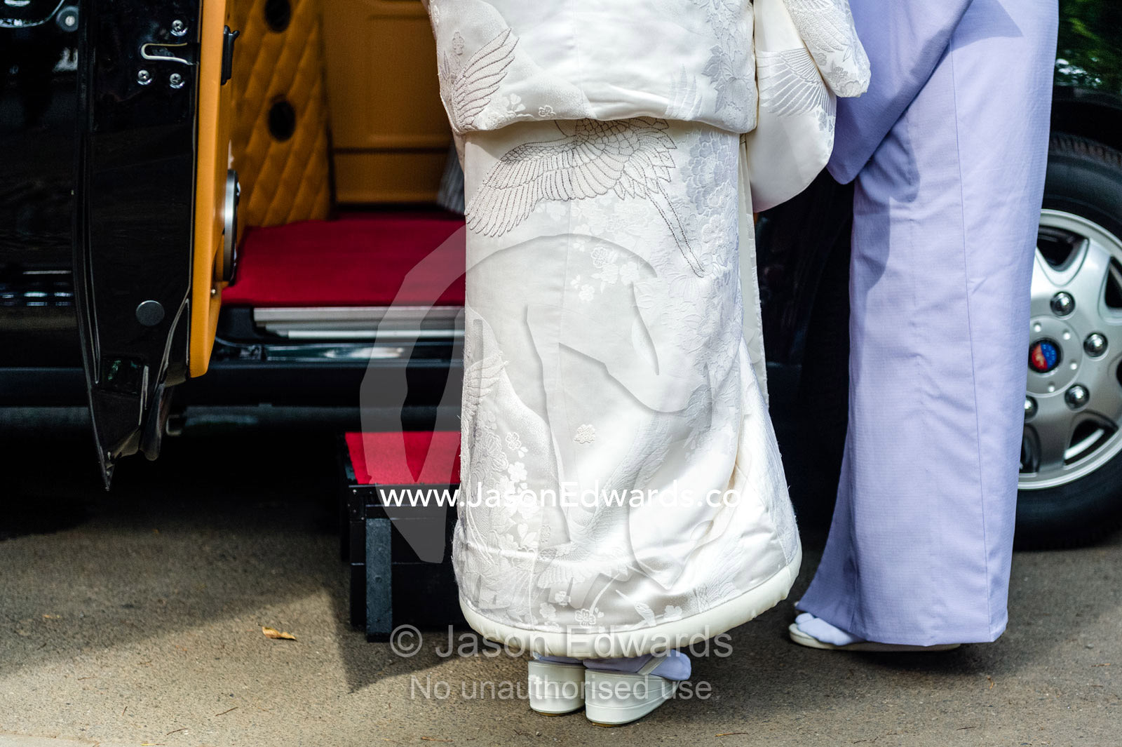 A Shinto bride wearing a wedding kimono called a uchikake and zori shoes getting into a limousine. Meiji Shrine, Shinto Shrine, Shibuya, Tokyo, Japan.