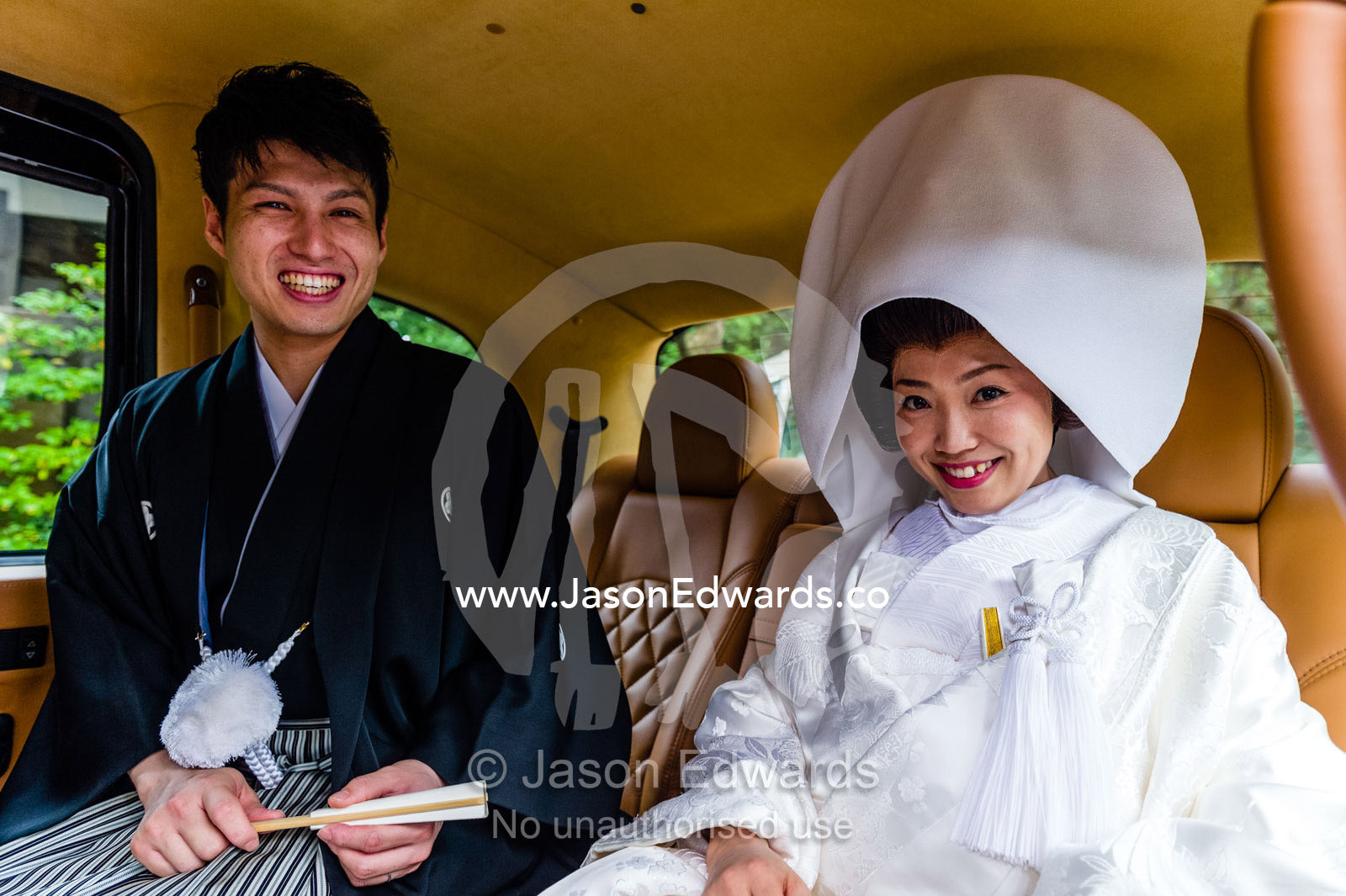 A Shinto groom and bride wearing a Tsunokakushi, traditional Japanese wedding headwear in a limousine. Meiji Shrine, Shinto Shrine, Shibuya, Tokyo, Japan.