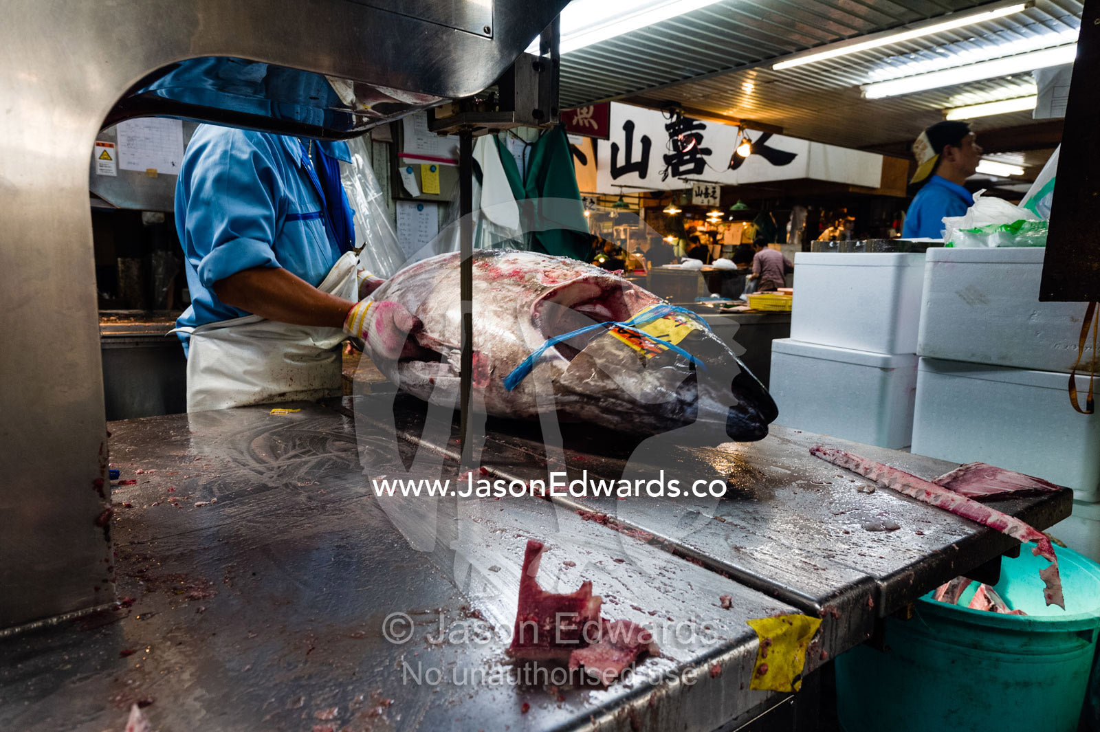A band saw cutting the head off a frozen tuna in a fish market. Tsukiji Market, Tsukiji, Chuo, Tokyo.
