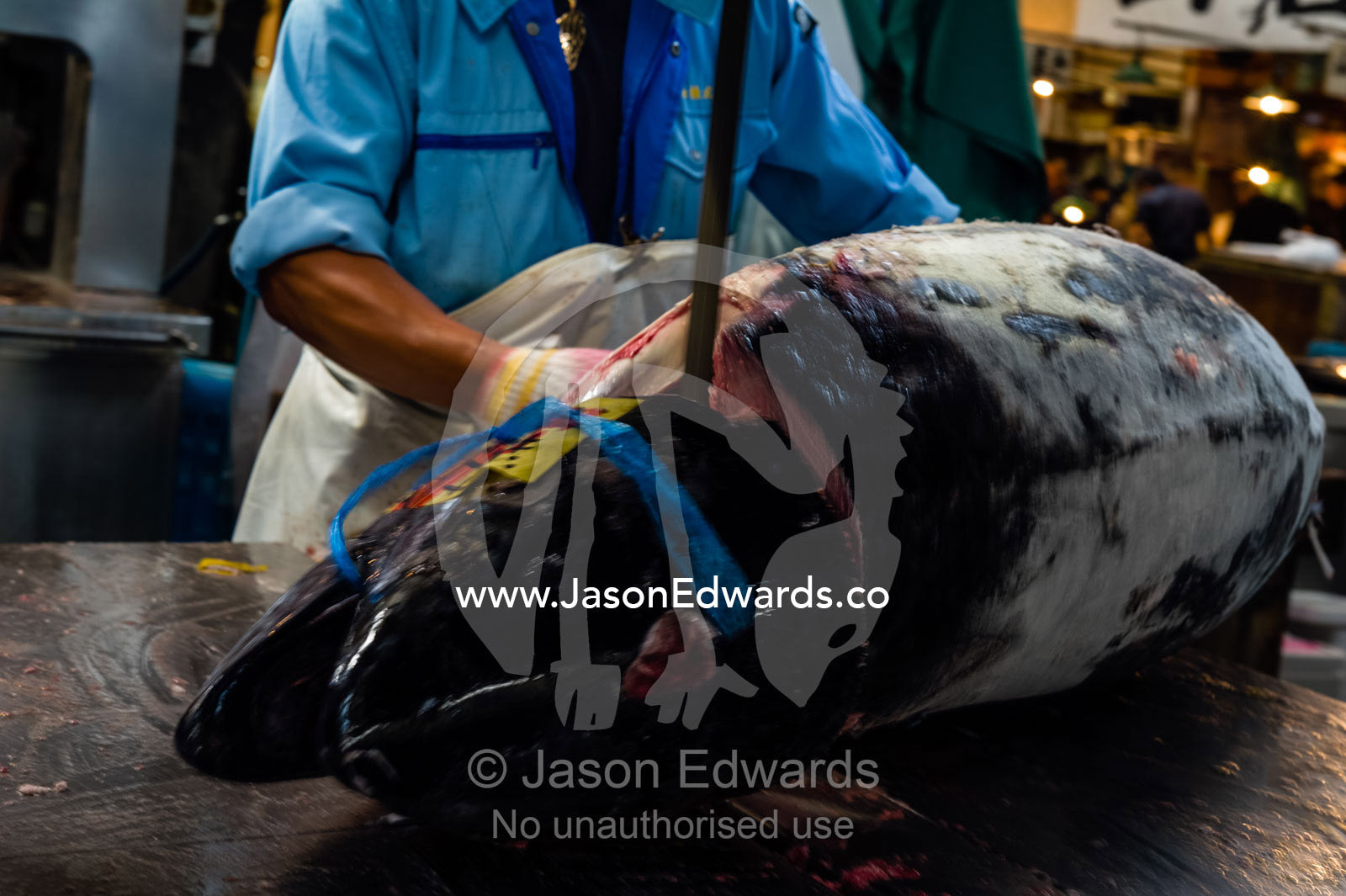 A band saw cutting the head off a frozen tuna in a fish market. Tsukiji Market, Tsukiji, Chuo, Tokyo.