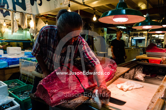 A fishmonger using a Yanagiba a traditional Japanese knife to cut tuna in a fish market. Tsukiji Market, Tsukiji, Chuo, Tokyo.