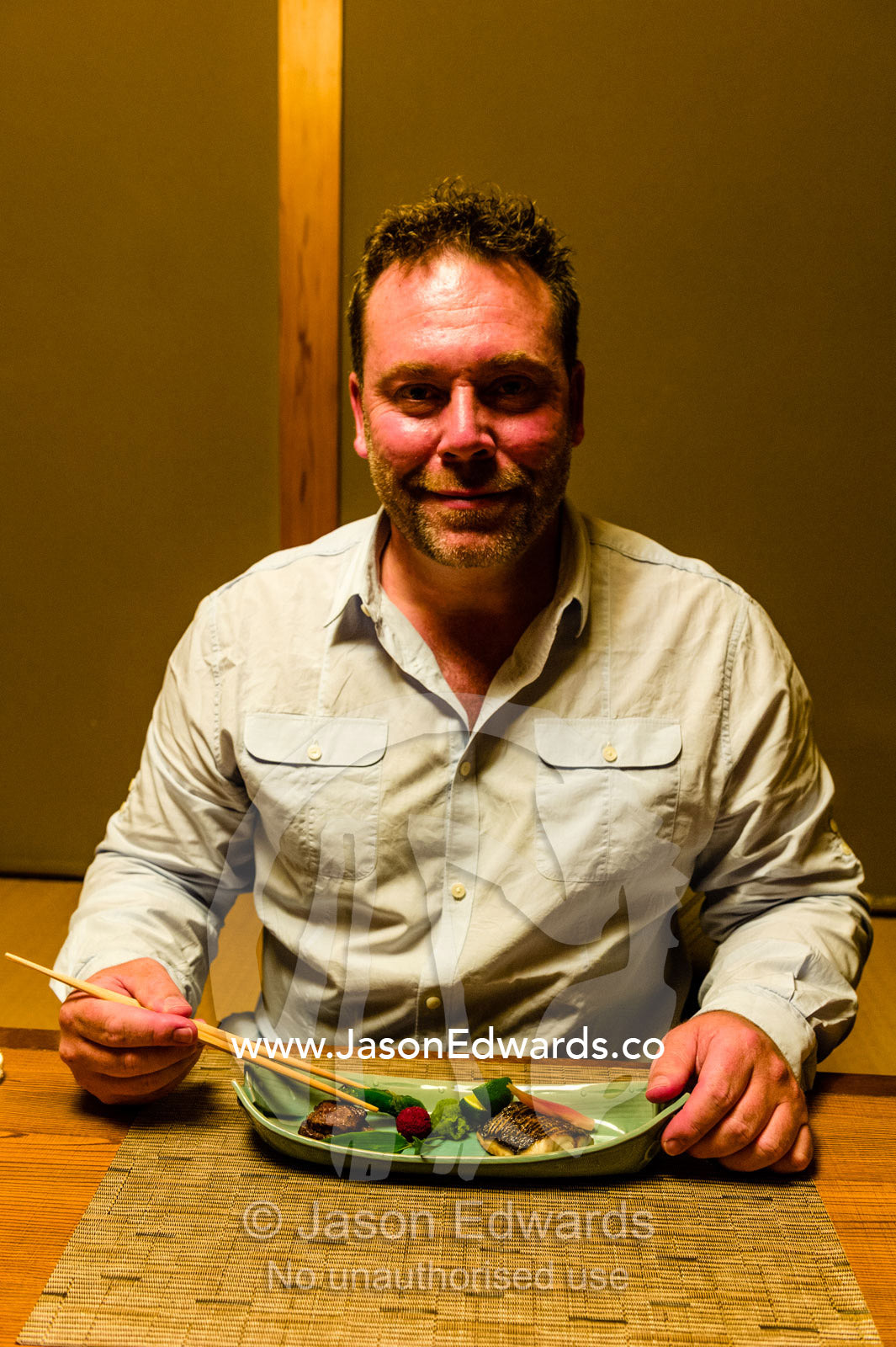 A man eating Kaiseki, a traditional multi-course Japanese dinner with chopsticks at a Zataku table. Unryu Onsen, Izu Peninsula, Shizuoka Prefecture, Japan.