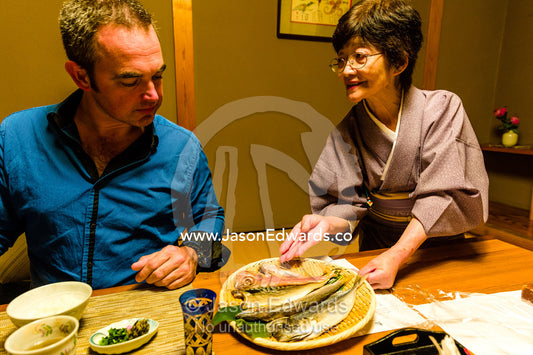 A man being served Kaiseki, a traditional multi-course Japanese dinner with chopsticks at a Zataku table. Unryu Onsen, Izu Peninsula, Shizuoka Prefecture, Japan.