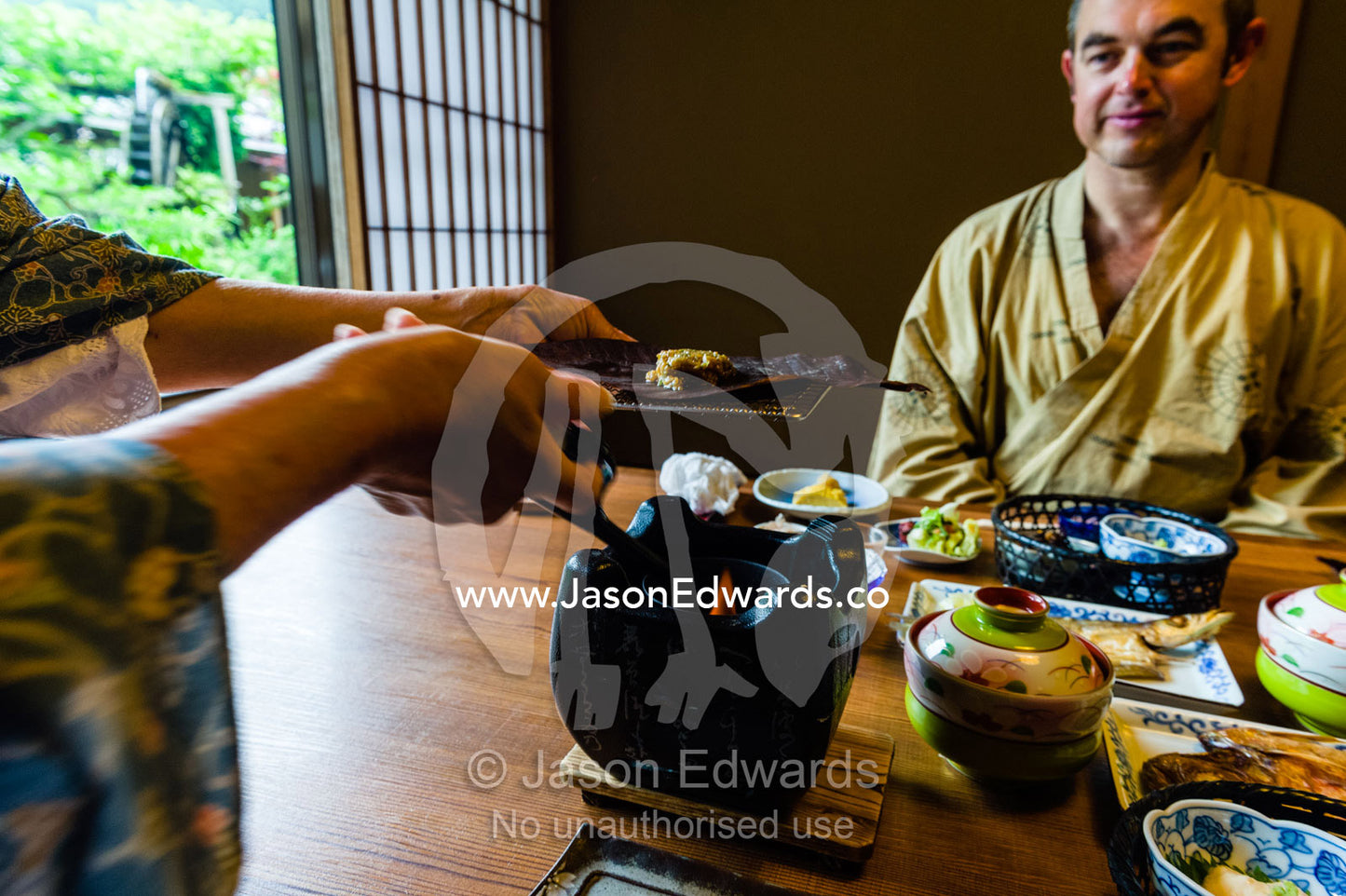 A man being served a traditional Japanese breakfast called Choshoku served at a zataku centre table. Unryu Onsen, Izu Peninsula, Shizuoka Prefecture, Japan.