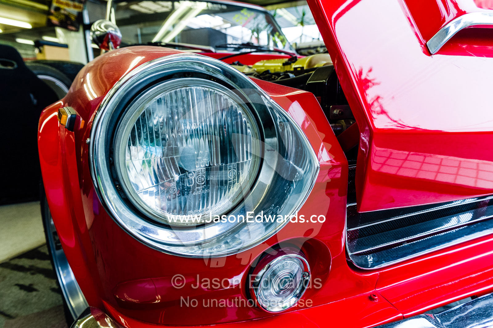 The chrome headlight of a bright red classic Datsun 2000 Sports car. Rocky Auto, Nagoya, Chubu Region, Japan.