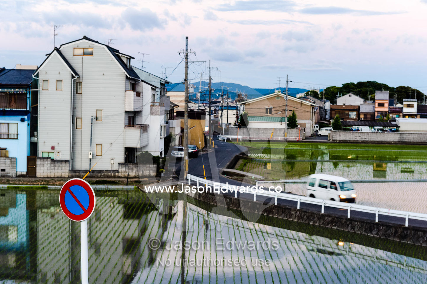 A road passes between houses and rice paddy's in a Japanese suburb. Arashiyama Bamboo Grove, Arashiyama District, Kyoto, Japan.