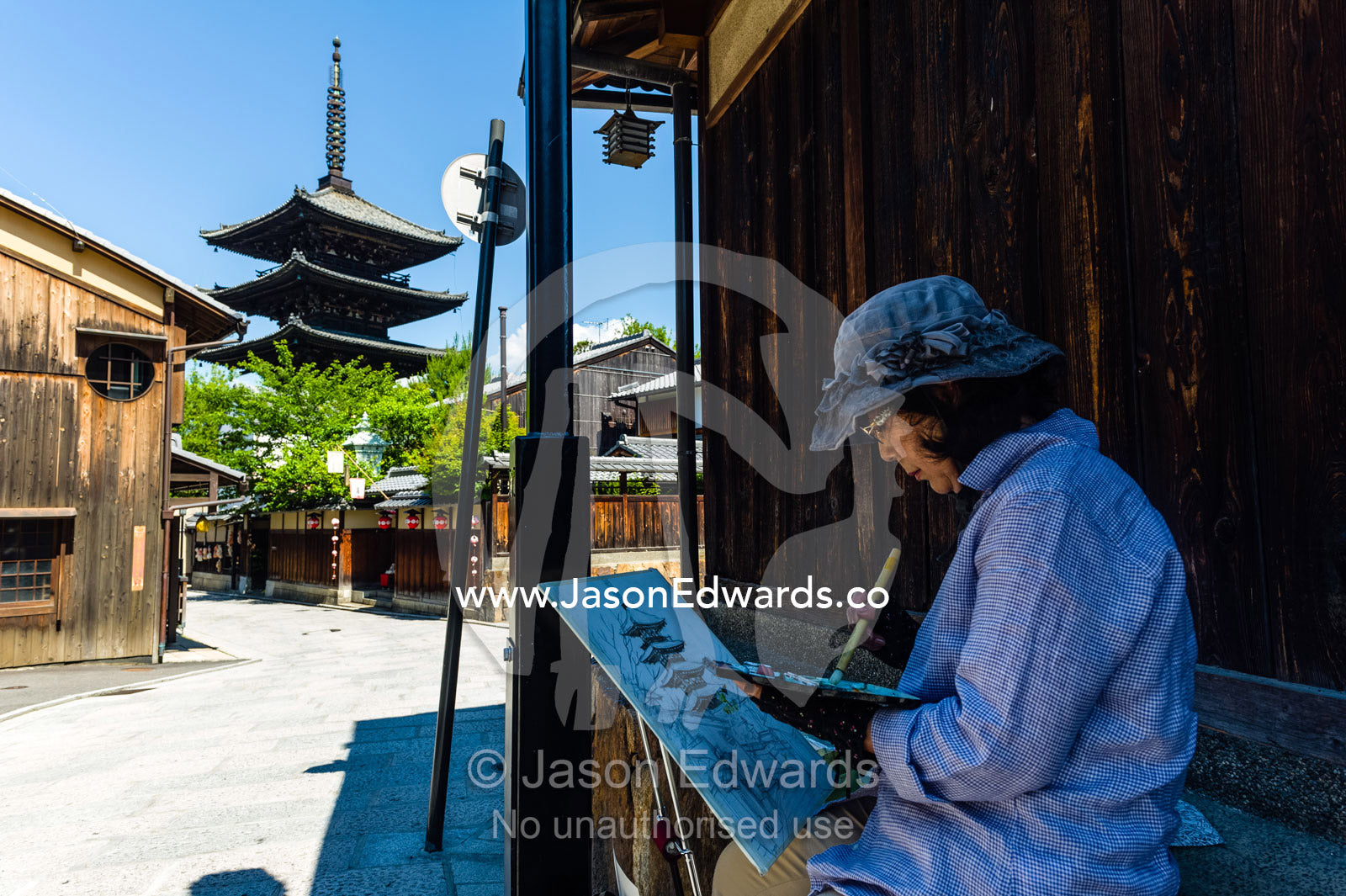 An artist paints a watercolour image of the Yasaka Pagoda using a soft brush and delicate strokes. Yasaka Pagoda, Hokanji Temple, Higashiyama, Kyoto, Japan.