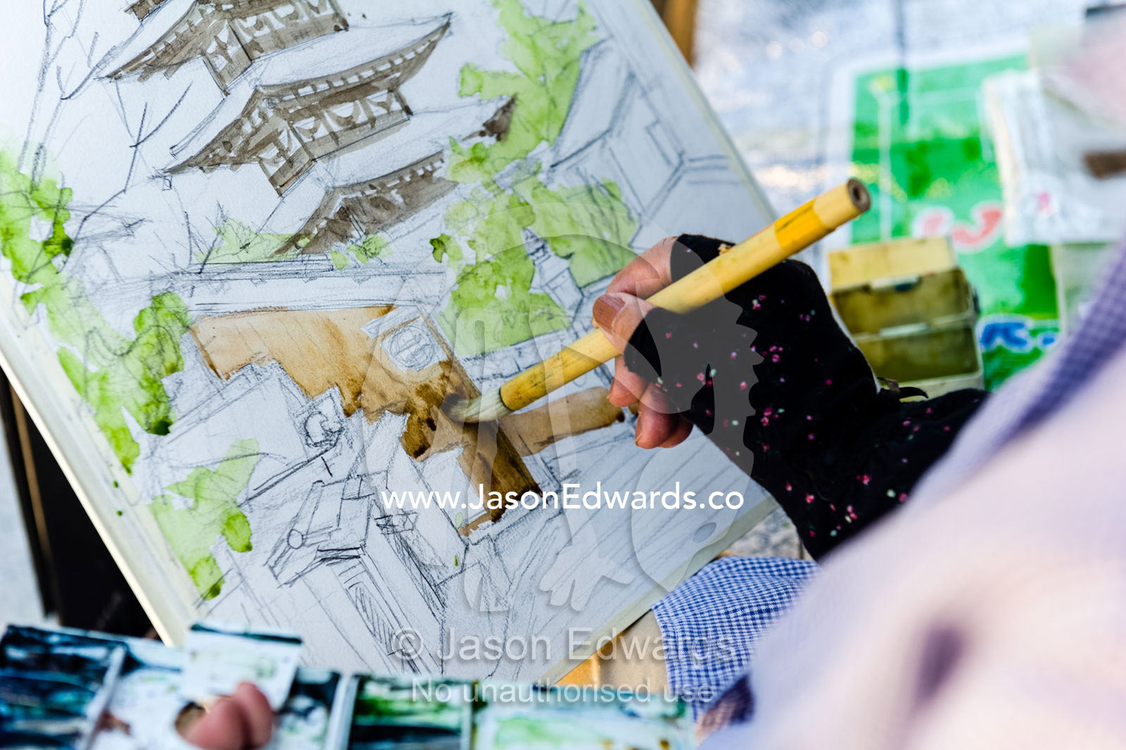 An artist paints a watercolour image of the Yasaka Pagoda using a soft brush and delicate strokes. Yasaka Pagoda, Hokanji Temple, Higashiyama, Kyoto, Japan.