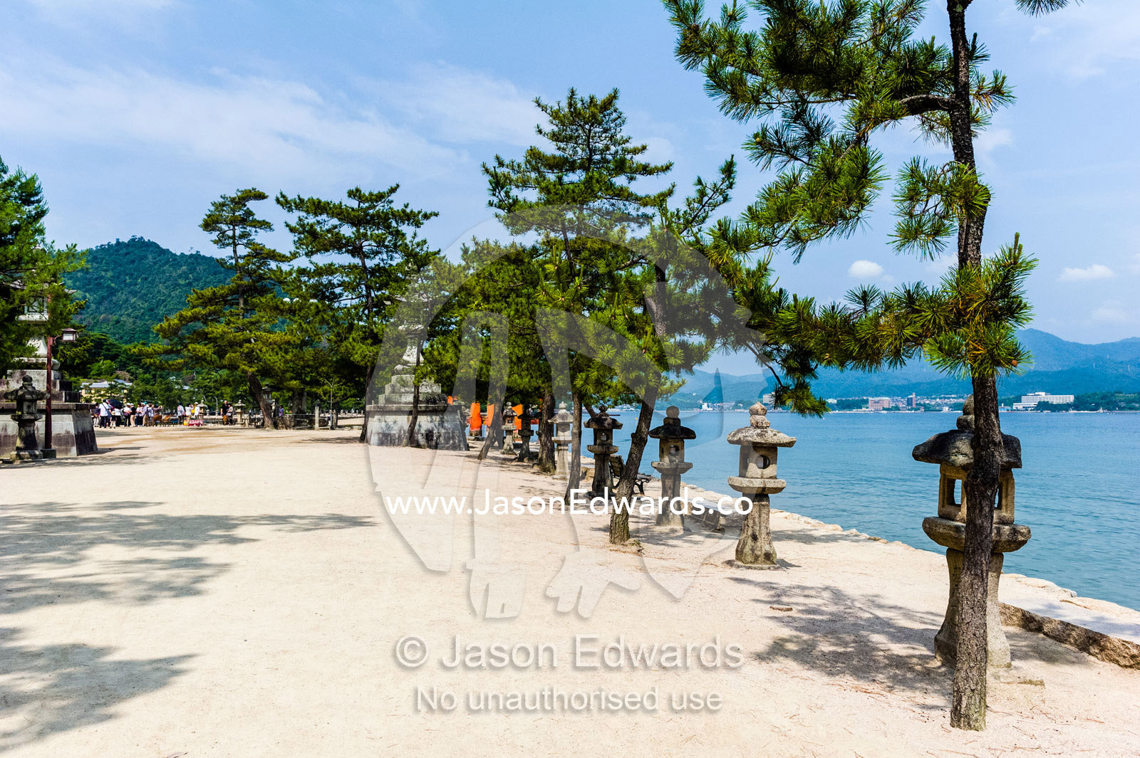 Japanese stone temple lanterns and Black Pine trees at the famous floating torii gate at Itsukushima Shrine. Itsukushima Shrine, Miyajima, Itsukushima Island, Inland Sea of Japan, Hiroshima Bay, Japan.