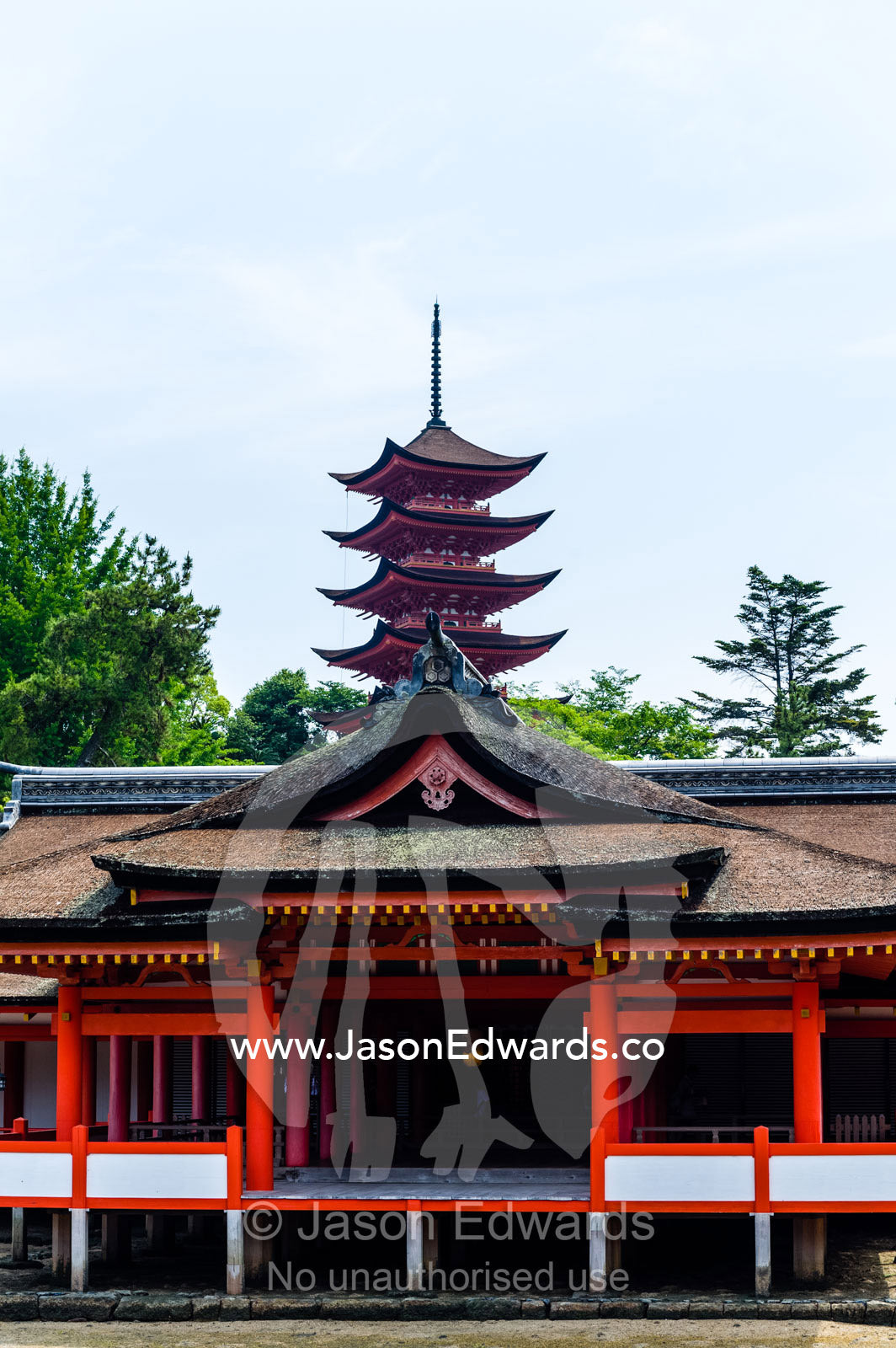 A tiered pagoda rises over the Itsukushima Shrine. Itsukushima Shrine, Miyajima, Itsukushima Island, Inland Sea of Japan, Hiroshima Bay, Japan.