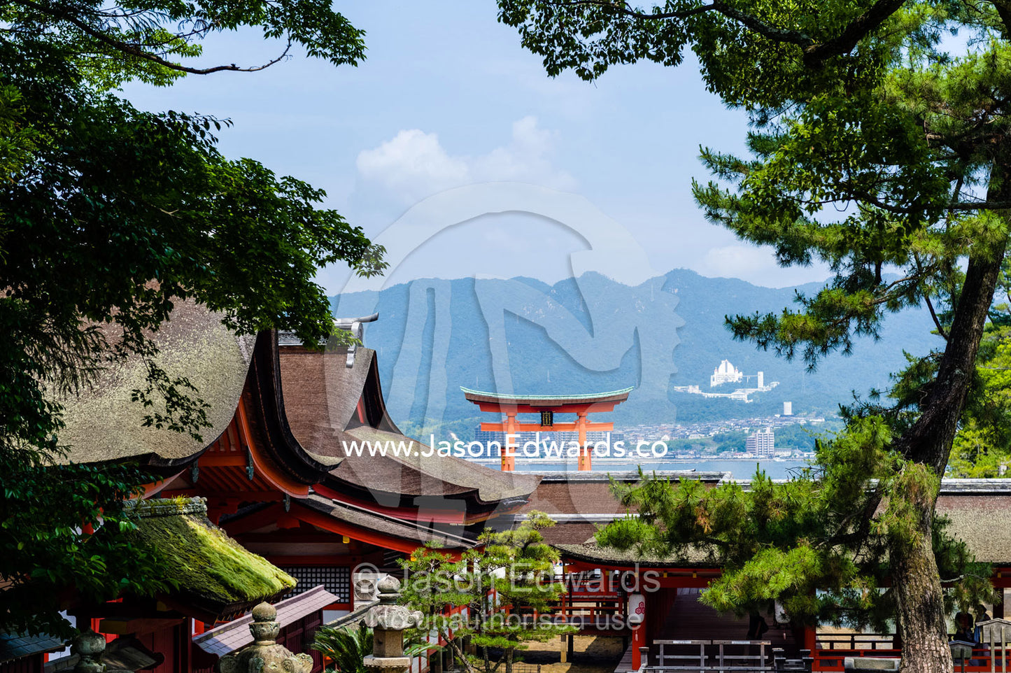 The famous torii gate at Itsukushima Shrine, is a Ryobu-style torii seen over the rooftops of a temple. Itsukushima Shrine, Miyajima, Itsukushima Island, Inland Sea of Japan, Hiroshima Bay, Japan.