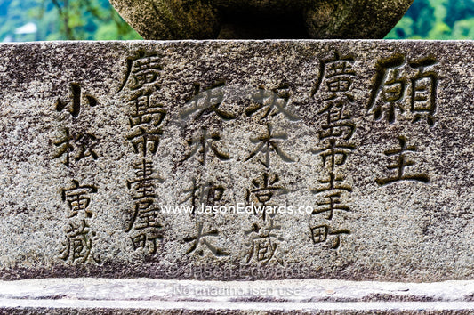 An inscription in Japanese lettering on a stone block in a shrine. Itsukushima Shrine, Miyajima, Itsukushima Island, Inland Sea of Japan, Hiroshima Bay, Japan.