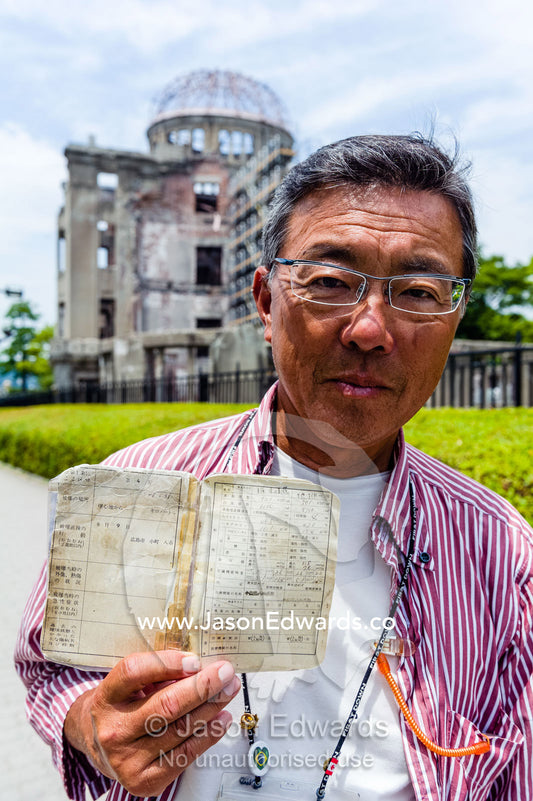 An in-utero survivor of the Hiroshima Atomic Bomb attack displays his official Japanese survivor documents. Hiroshima Peace Memorial Park, Hiroshima, Honshu Island, Japan.