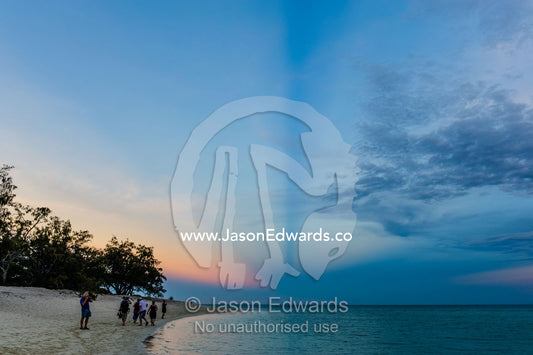 A group of people exploring a tropical beach at sunset. Shark Bay, Heron Island, Great Barrier Reef, Queensland, Australia.