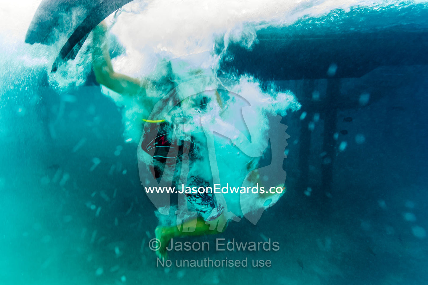 A swimmer plunges into the ocean from a jetty creating lots of bubbles. Heron Island Harbour, Heron Island, Great Barrier Reef, Queensland, Australia.