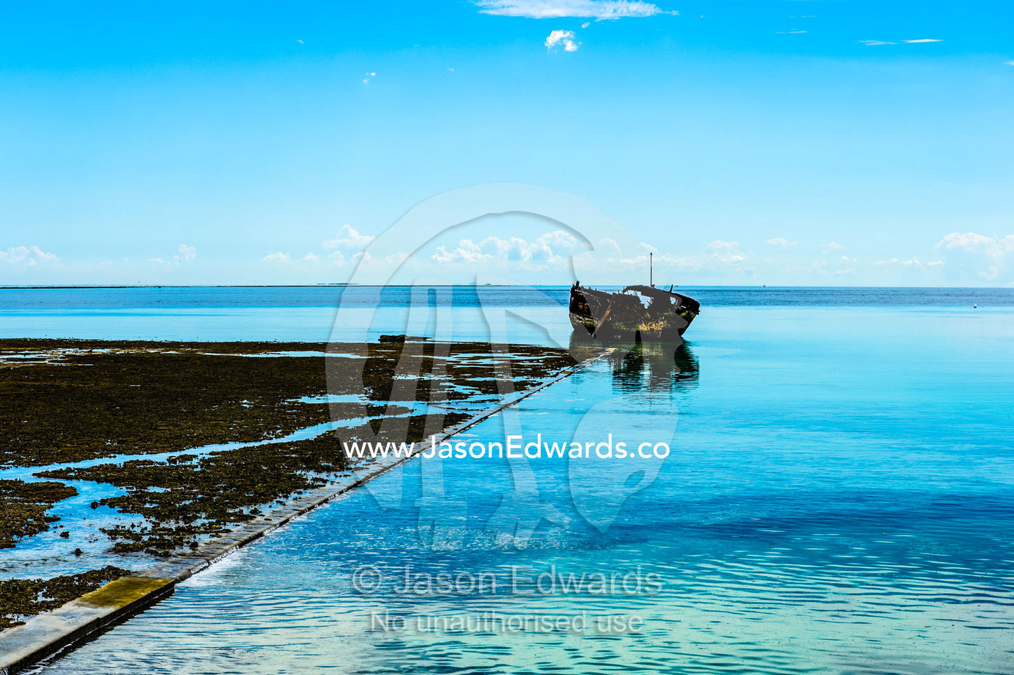 A harbour retaining wall, shipwreck and coral reef at low tide. Wreck Beach, Heron Island, Great Barrier Reef, Queensland, Australia.
