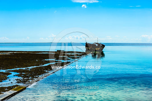 A harbour retaining wall, shipwreck and coral reef at low tide. Wreck Beach, Heron Island, Great Barrier Reef, Queensland, Australia.