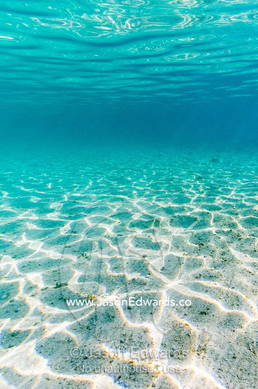 The shallow turquoise waters and white sandy ocean floor near a tropical island. Wreck Beach, Heron Island, Great Barrier Reef, Queensland, Australia.