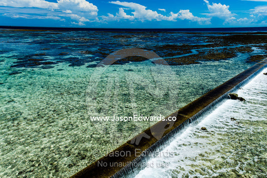 Water from the rising tide spills over a coral reef and harbour retaining wall. Heron Island Harbour, Heron Island, Great Barrier Reef, Queensland, Australia.