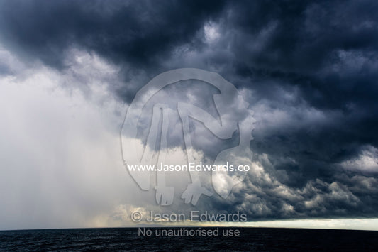 A menacing tropical rainstorm darkens the ocean and the sky. Gladstone, Queensland, Australia.