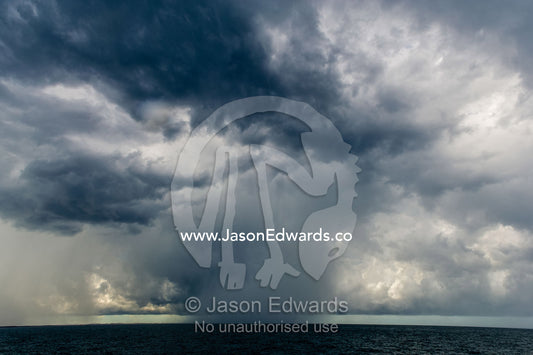 A menacing tropical rainstorm darkens the ocean and the sky. Gladstone, Queensland, Australia.