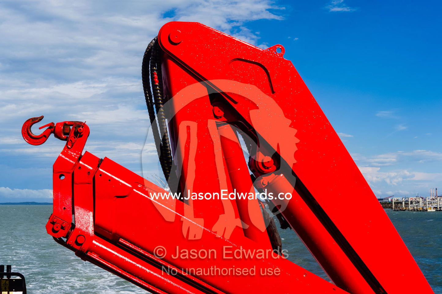 A bright red crane on a passenger ferry used for lifting cargo. Gladstone, Queensland, Australia.