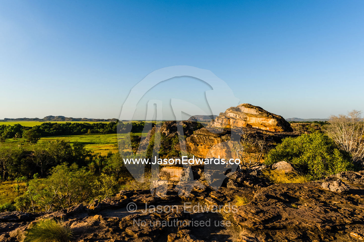 A rugged sandstone escarpment overlooking a floodplain at sunset. Ubirr, Nadab floodplain, Kakadu National Park, Northern Territory, Australia.