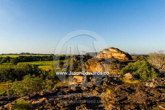 A rugged sandstone escarpment overlooking a floodplain at sunset. Ubirr, Nadab floodplain, Kakadu National Park, Northern Territory, Australia.