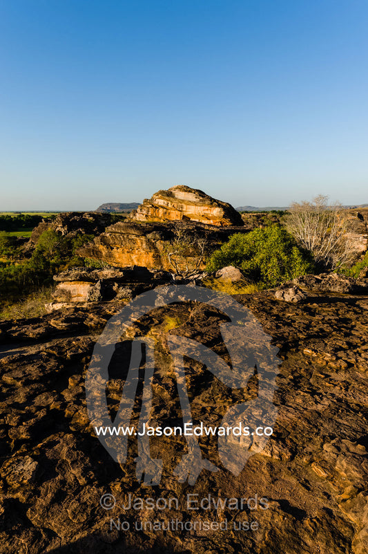 A rugged sandstone escarpment overlooking a floodplain at sunset. Ubirr, Nadab floodplain, Kakadu National Park, Northern Territory, Australia.