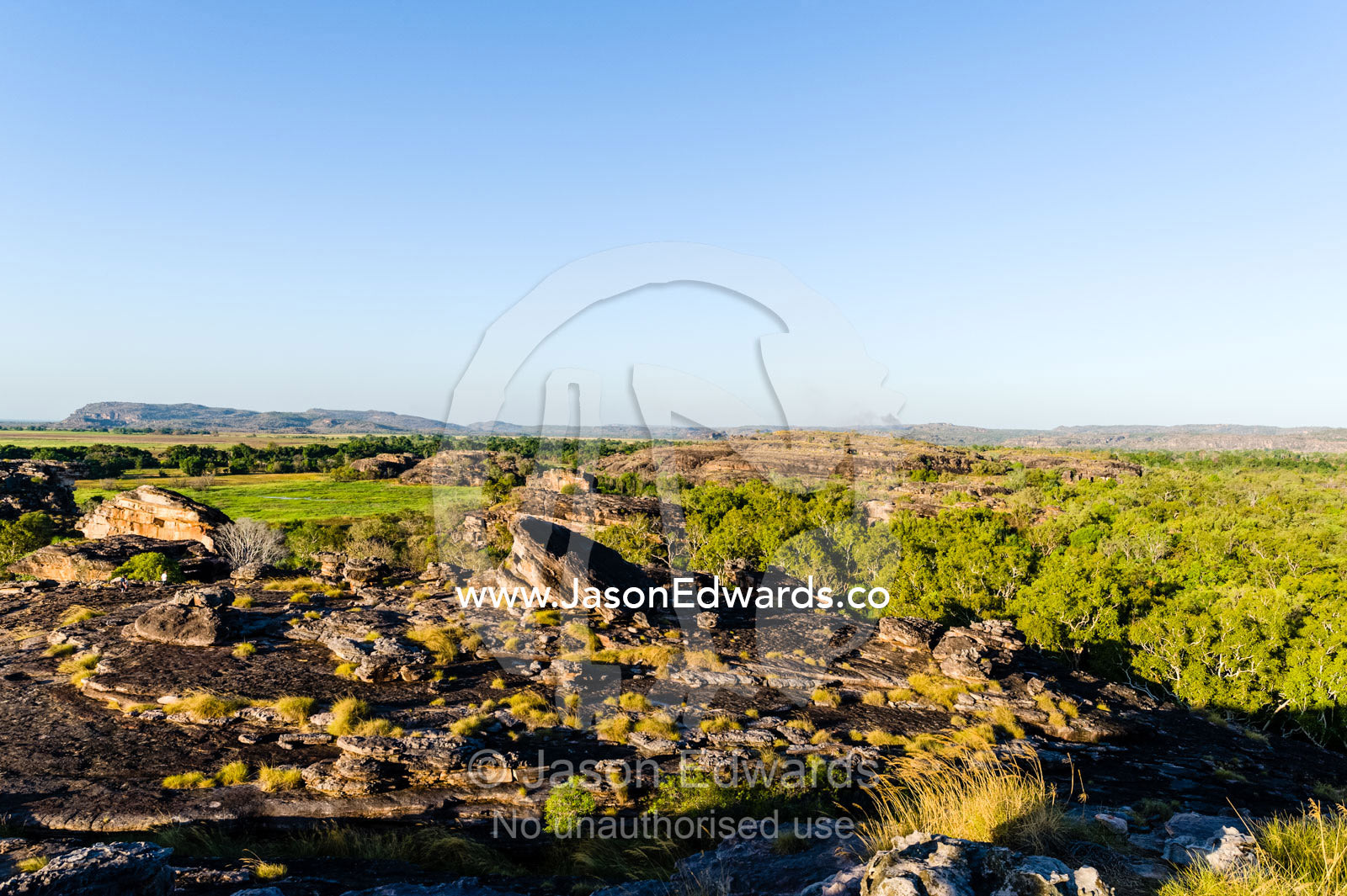 A rugged sandstone escarpment overlooking a floodplain at sunset. Ubirr, Nadab floodplain, Kakadu National Park, Northern Territory, Australia.