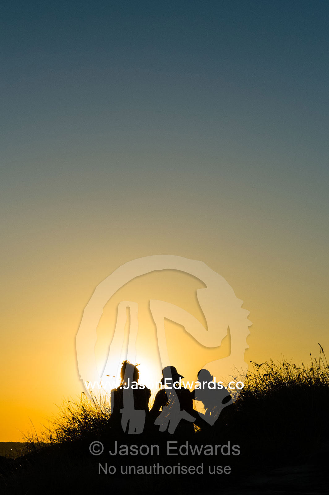 The silhouette of friends watching a famous Top End, sunset from an escarpment over a floodplain. Ubirr, Nadab floodplain, Kakadu National Park, Northern Territory, Australia.