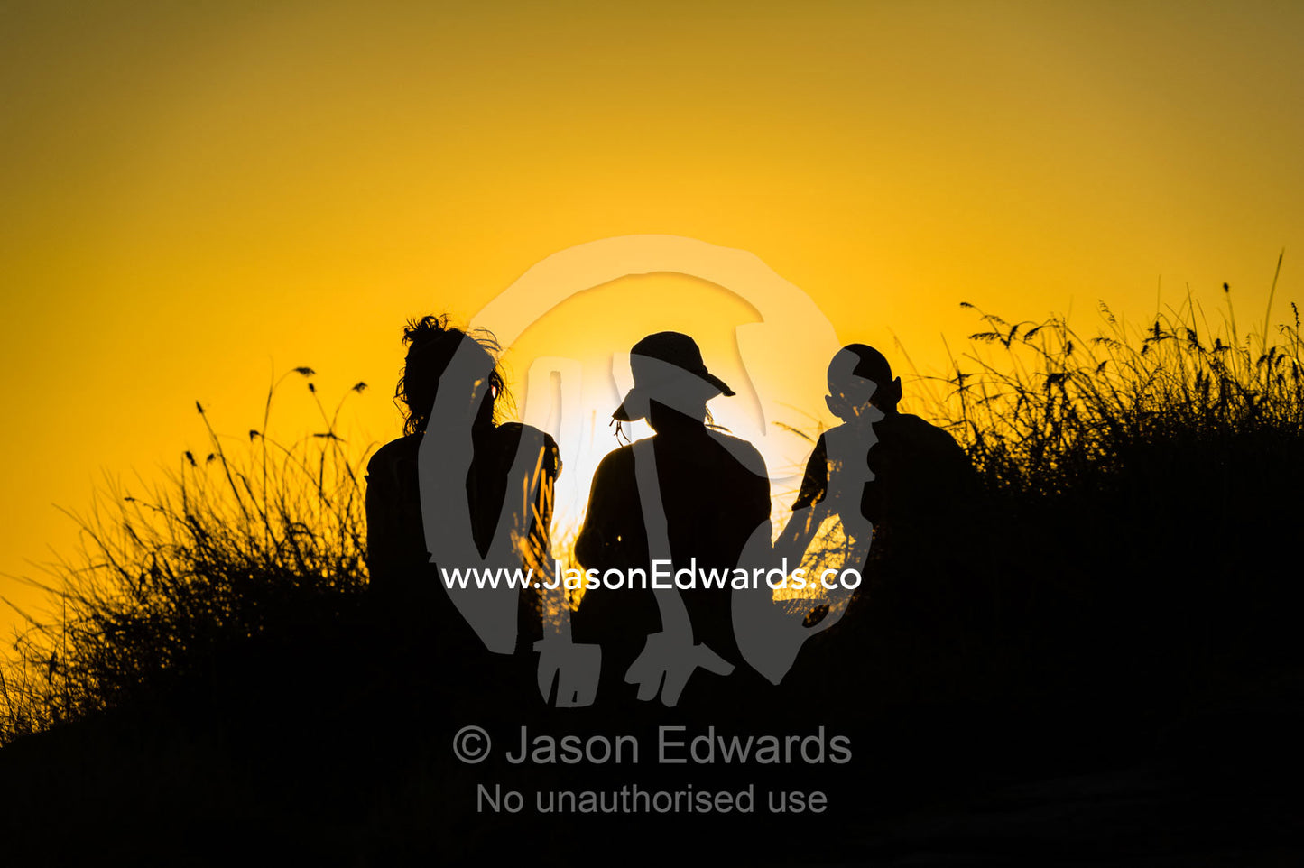 The silhouette of friends watching a famous Top End, sunset from an escarpment over a floodplain. Ubirr, Nadab floodplain, Kakadu National Park, Northern Territory, Australia.