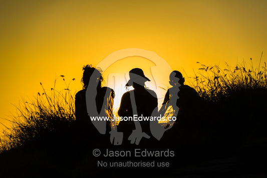 The silhouette of friends watching a famous Top End, sunset from an escarpment over a floodplain. Ubirr, Nadab floodplain, Kakadu National Park, Northern Territory, Australia.