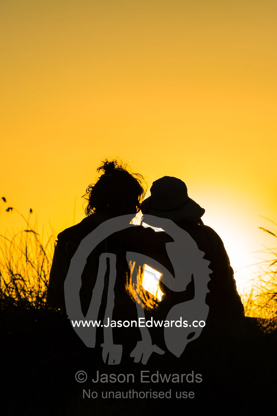 The silhouette of friends watching a famous Top End, sunset from an escarpment over a floodplain. Ubirr, Nadab floodplain, Kakadu National Park, Northern Territory, Australia.