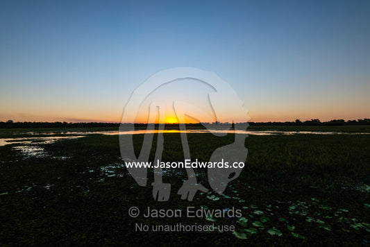 Sunset falls over a still floodplain in the dry season. Yellow Water Billabong, Cooinda, Kakadu National Park, Northern Territory, Australia.