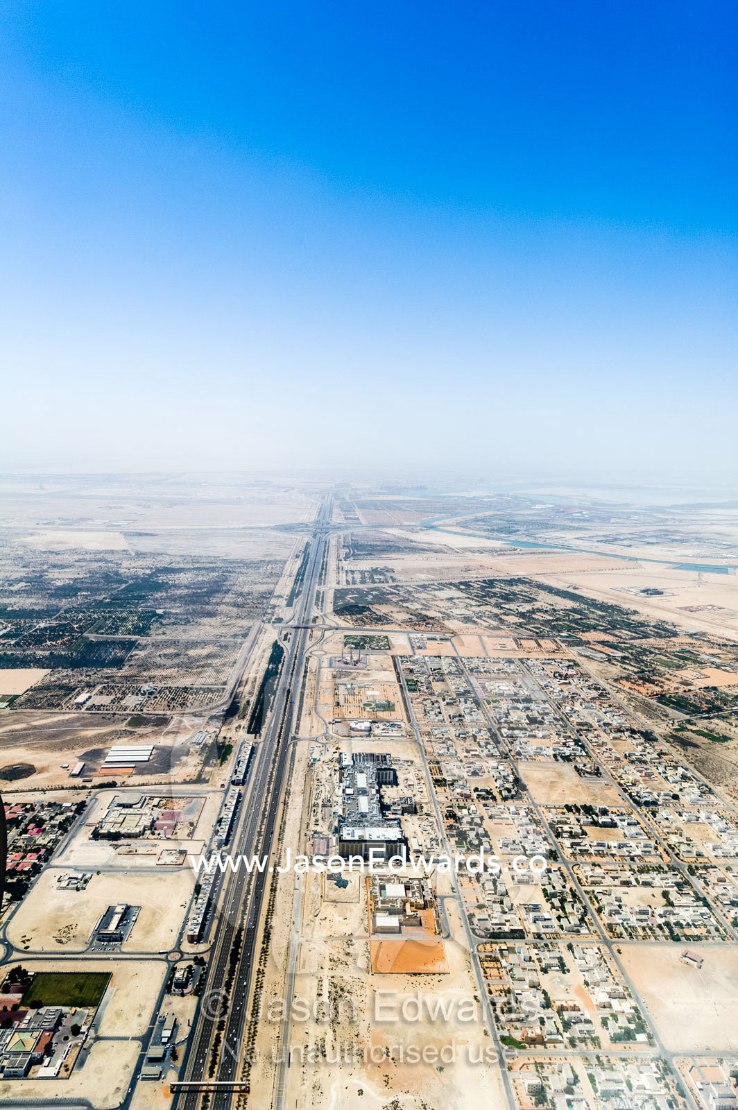 A highway passes factories and residential estates in the desert. Emirate of Abu Dhabi, Abu Dhabi, Persian Gulf, United Arab Emirates.